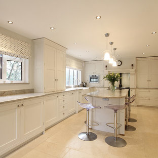 Photo of a large traditional kitchen in Hampshire with a farmhouse sink, shaker cabinets, white cabinets, granite benchtops, coloured appliances, limestone floors and with island.