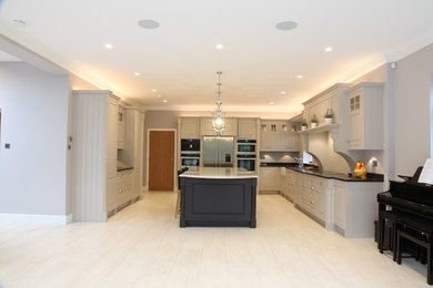Large l-shaped kitchen/diner in Other with a belfast sink, raised-panel cabinets, quartz worktops, stainless steel appliances, an island and brown worktops.