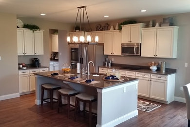 Example of a large classic medium tone wood floor eat-in kitchen design in St Louis with a double-bowl sink, recessed-panel cabinets, white cabinets, quartz countertops, brown backsplash, stone slab backsplash, stainless steel appliances and an island