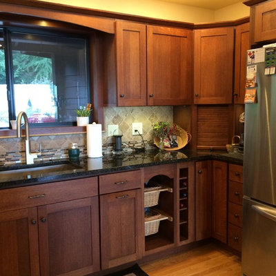 Eat-in kitchen - mid-sized craftsman u-shaped light wood floor eat-in kitchen idea in Seattle with an undermount sink, shaker cabinets, dark wood cabinets, granite countertops, beige backsplash, stone tile backsplash, stainless steel appliances and a peninsula