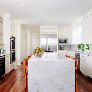 Contemporary kitchen remodeling - Example of a trendy u-shaped medium tone wood floor and brown floor kitchen design in Minneapolis with flat-panel cabinets, white cabinets, stainless steel appliances, an island, white countertops, an undermount sink and white backsplash
