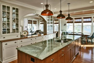 Eat-in kitchen - large traditional l-shaped medium tone wood floor and brown floor eat-in kitchen idea in Boston with a double-bowl sink, shaker cabinets, beige cabinets, wood countertops, stainless steel appliances, an island, white backsplash and subway tile backsplash