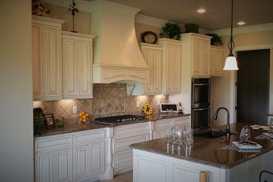 Farmhouse l-shaped eat-in kitchen photo in Dallas with an undermount sink, raised-panel cabinets, white cabinets, granite countertops, beige backsplash, cement tile backsplash, stainless steel appliances and an island
