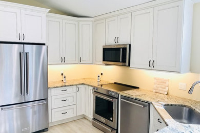 Imagen de cocina tradicional renovada de tamaño medio con puertas de armario blancas, electrodomésticos de acero inoxidable y una isla