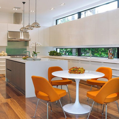Large trendy l-shaped medium tone wood floor eat-in kitchen photo in Miami with an undermount sink, flat-panel cabinets, white cabinets, stainless steel appliances, an island and solid surface countertops