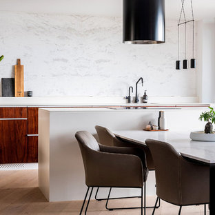 Design ideas for a small contemporary galley eat-in kitchen in Sydney with flat-panel cabinets, marble benchtops, white splashback, marble splashback, light hardwood floors, with island, white benchtop, dark wood cabinets and brown floor.
