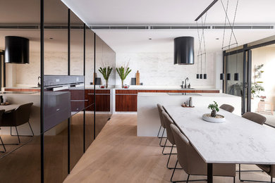 Inspiration for a small contemporary galley kitchen/diner in Sydney with a submerged sink, flat-panel cabinets, marble worktops, white splashback, marble splashback, light hardwood flooring, an island, white worktops, dark wood cabinets and brown floors.