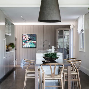 This is an example of a traditional galley eat-in kitchen in Sydney with an undermount sink, flat-panel cabinets, grey cabinets, black appliances, dark hardwood floors, with island and white benchtop.