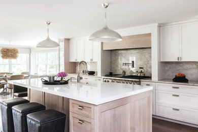 Inspiration for a transitional light wood floor and brown floor eat-in kitchen remodel in New York with shaker cabinets, white cabinets, gray backsplash, stainless steel appliances, an island, marble backsplash, an undermount sink and white countertops