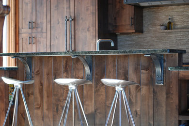 Aménagement d'une cuisine montagne en bois foncé de taille moyenne avec un placard à porte shaker, un plan de travail en granite, une crédence beige et un électroménager en acier inoxydable.