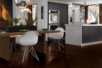 Imagen de cocina minimalista pequeña con electrodomésticos de acero inoxidable, suelo de madera oscura, una isla y suelo marrón