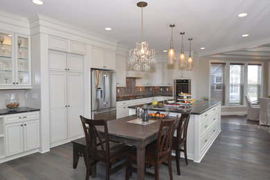 Inspiration for a mid-sized modern single-wall light wood floor eat-in kitchen remodel in Milwaukee with flat-panel cabinets, white cabinets, multicolored backsplash, stainless steel appliances and an island