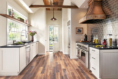 This is an example of a medium sized farmhouse galley kitchen/diner in San Diego with shaker cabinets, white cabinets, black splashback, metro tiled splashback, stainless steel appliances, dark hardwood flooring, no island, a submerged sink, soapstone worktops and brown floors.