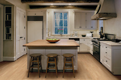Cottage l-shaped light wood floor and beige floor enclosed kitchen photo in San Francisco with shaker cabinets, white cabinets, wood countertops, paneled appliances and an island