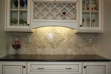 Mid-sized elegant u-shaped enclosed kitchen photo in Atlanta with raised-panel cabinets, distressed cabinets, granite countertops, beige backsplash, stone tile backsplash and an island