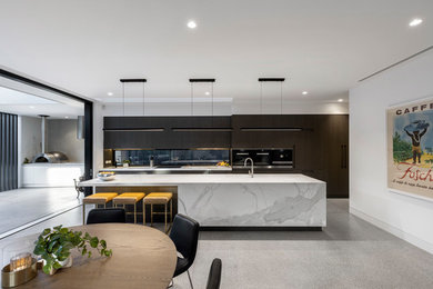Immagine di un grande cucina con isola centrale contemporaneo con lavello sottopiano, top in marmo, paraspruzzi con lastra di vetro, pavimento in cemento, pavimento grigio e top bianco