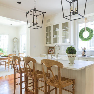 Mid-sized elegant l-shaped kitchen photo in New Orleans with glass-front cabinets, white cabinets, multicolored backsplash and an island