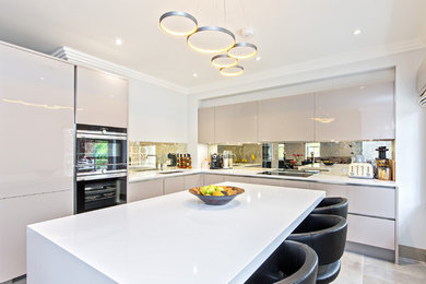 Design ideas for an expansive contemporary l-shaped open plan kitchen in London with a submerged sink, glass-front cabinets, beige cabinets, onyx worktops, metallic splashback, mirror splashback, integrated appliances, ceramic flooring and an island.