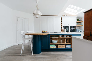 This is an example of a medium sized classic u-shaped kitchen/diner in Hertfordshire with a submerged sink, shaker cabinets, quartz worktops, porcelain flooring, an island, multi-coloured floors and white worktops.