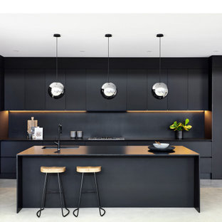 Photo of a large contemporary galley kitchen in Sydney with an undermount sink, flat-panel cabinets, black cabinets, concrete floors, grey floor, black benchtop, quartz benchtops, black splashback, stone slab splashback, stainless steel appliances and no island.