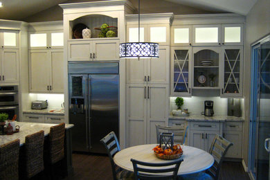 Eat-in kitchen - eat-in kitchen idea in Phoenix with a farmhouse sink, shaker cabinets, white cabinets, granite countertops, white backsplash, ceramic backsplash, stainless steel appliances and an island