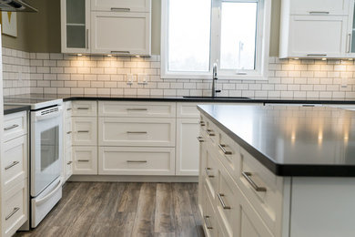 Example of a mid-sized minimalist l-shaped laminate floor eat-in kitchen design in Other with an undermount sink, shaker cabinets, white cabinets, quartz countertops, white backsplash, subway tile backsplash, stainless steel appliances and an island