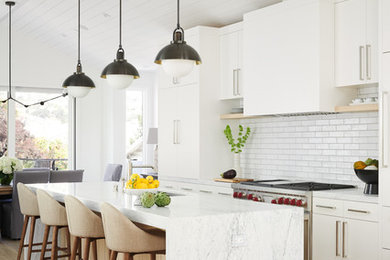サンフランシスコにある高級な広いトランジショナルスタイルのおしゃれなキッチン (アンダーカウンターシンク、フラットパネル扉のキャビネット、白いキャビネット、大理石カウンター、白いキッチンパネル、セラミックタイルのキッチンパネル、パネルと同色の調理設備、淡色無垢フローリング、白いキッチンカウンター、茶色い床) の写真
