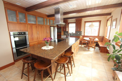 他の地域にある広いトラディショナルスタイルのおしゃれなキッチン (中間色木目調キャビネット、クオーツストーンカウンター、シルバーの調理設備、セラミックタイルの床) の写真
