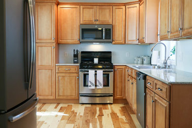 Klassische Wohnküche mit Waschbecken, profilierten Schrankfronten, hellbraunen Holzschränken, Granit-Arbeitsplatte und braunem Holzboden in Bridgeport