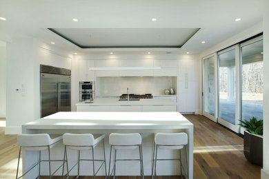 Example of a huge trendy l-shaped medium tone wood floor open concept kitchen design in Toronto with a single-bowl sink, flat-panel cabinets, white cabinets, quartz countertops, white backsplash, two islands and stainless steel appliances