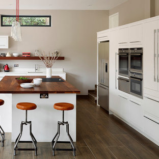 Modelo de cocina escandinava con fregadero bajoencimera, armarios con paneles lisos, puertas de armario blancas, encimera de madera, electrodomésticos de acero inoxidable, suelo de madera oscura y una isla