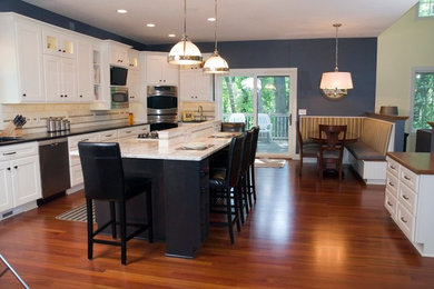 Photo of a large classic l-shaped open plan kitchen in Minneapolis with a submerged sink, recessed-panel cabinets, white cabinets, granite worktops, white splashback, stone tiled splashback, stainless steel appliances and dark hardwood flooring.