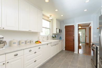 Example of a mid-sized transitional galley enclosed kitchen design in New York with white cabinets, marble countertops, white backsplash, subway tile backsplash, stainless steel appliances and no island