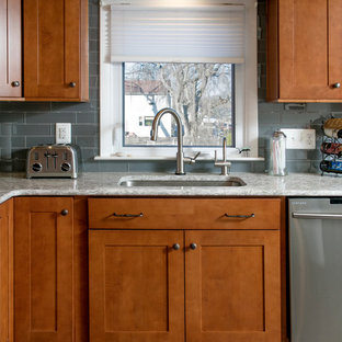 Photo of a mid-sized traditional l-shaped separate kitchen in Philadelphia with an undermount sink, shaker cabinets, medium wood cabinets, quartz benchtops, glass tile splashback, stainless steel appliances, vinyl floors, with island, grey splashback and grey floor.