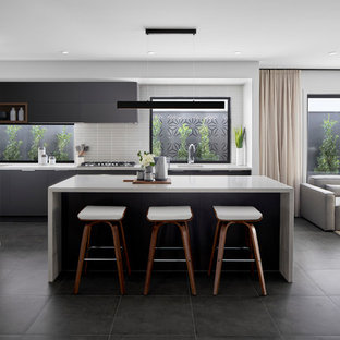 Photo of a contemporary l-shaped open plan kitchen in Melbourne with an undermount sink, flat-panel cabinets, grey cabinets, white splashback, mosaic tile splashback, stainless steel appliances, with island, grey floor and white benchtop.