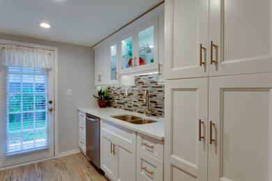Enclosed kitchen - mid-sized transitional galley vinyl floor and brown floor enclosed kitchen idea in Tampa with a double-bowl sink, recessed-panel cabinets, white cabinets, quartzite countertops, multicolored backsplash, matchstick tile backsplash, stainless steel appliances, no island and white countertops