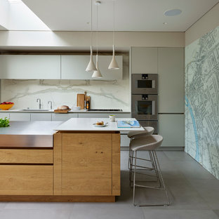 Photo of a large contemporary single-wall kitchen in London with flat-panel cabinets, composite countertops, white splashback, an island, grey floors, white worktops, a submerged sink and grey cabinets.