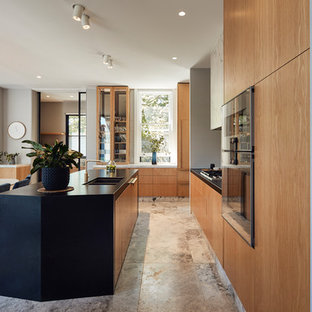 This is an example of a mid-sized contemporary l-shaped open plan kitchen in Melbourne with an undermount sink, flat-panel cabinets, medium wood cabinets, granite benchtops, white splashback, marble splashback, panelled appliances, limestone floors, with island, grey floor and black benchtop.