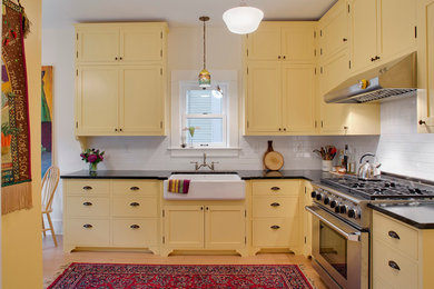 ポートランドにあるトラディショナルスタイルのおしゃれなキッチン (サブウェイタイルのキッチンパネル、エプロンフロントシンク、シェーカースタイル扉のキャビネット、黄色いキャビネット、白いキッチンパネル、ソープストーンカウンター、シルバーの調理設備) の写真
