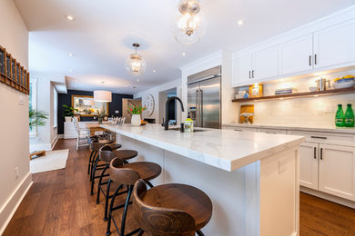 Mid-sized minimalist l-shaped medium tone wood floor and brown floor eat-in kitchen photo in Other with an undermount sink, shaker cabinets, white cabinets, white backsplash, stainless steel appliances, an island and white countertops