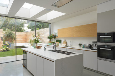 Esempio di una cucina design di medie dimensioni con lavello integrato, ante lisce, ante grigie, top in superficie solida, paraspruzzi bianco, elettrodomestici da incasso, pavimento in cemento e pavimento grigio