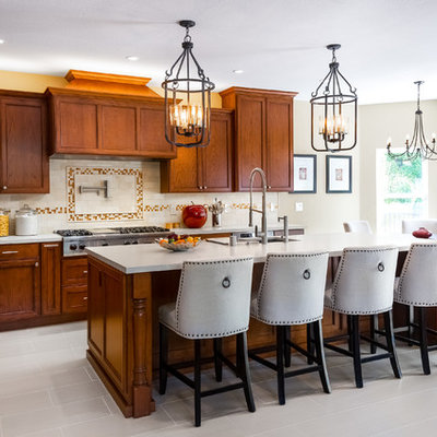 Inspiration for a large timeless l-shaped porcelain tile and beige floor eat-in kitchen remodel in San Francisco with an undermount sink, recessed-panel cabinets, medium tone wood cabinets, quartz countertops, beige backsplash, stone tile backsplash, stainless steel appliances, an island and beige countertops