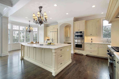 Inspiration for a large timeless l-shaped dark wood floor open concept kitchen remodel in Atlanta with a drop-in sink, beaded inset cabinets, white cabinets, marble countertops, white backsplash, subway tile backsplash, stainless steel appliances and an island