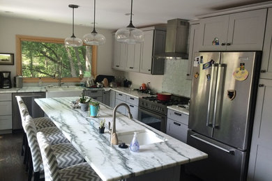 Ejemplo de cocina comedor moderna pequeña con puertas de armario grises, encimera de mármol, salpicadero verde, electrodomésticos de acero inoxidable, una isla y suelo marrón