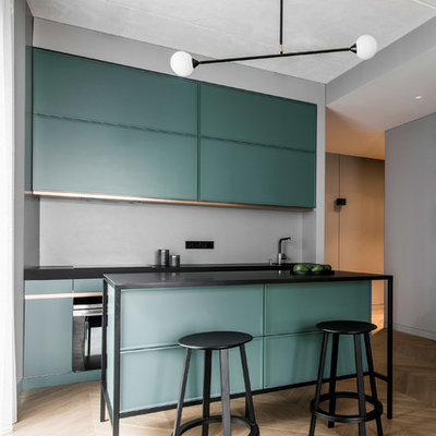 Example of a trendy galley light wood floor and beige floor kitchen design in New York with flat-panel cabinets, green cabinets, gray backsplash, an island and black countertops