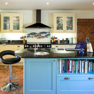 Medium sized country u-shaped open plan kitchen in Hertfordshire with a built-in sink, shaker cabinets, blue cabinets, granite worktops, white splashback, brick splashback, white appliances, ceramic flooring, an island and brown floors.