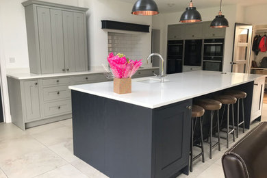 Photo of a large modern kitchen/diner in Cambridgeshire with a submerged sink, quartz worktops, black appliances and an island.