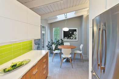 Example of a mid-sized 1960s u-shaped porcelain tile enclosed kitchen design in DC Metro with a double-bowl sink, flat-panel cabinets, white cabinets, quartzite countertops, green backsplash, glass tile backsplash and stainless steel appliances