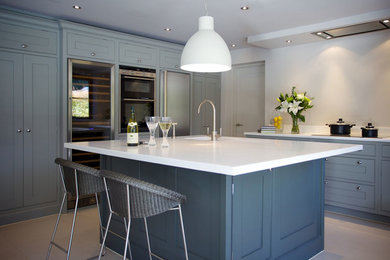 Klassische Küche mit integriertem Waschbecken, Schrankfronten im Shaker-Stil, blauen Schränken, Granit-Arbeitsplatte, Küchengeräten aus Edelstahl, Kücheninsel und weißer Arbeitsplatte in Cheshire