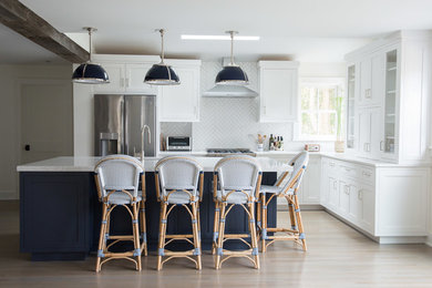 Eat-in kitchen - farmhouse galley light wood floor and beige floor eat-in kitchen idea in New York with shaker cabinets, white cabinets, white backsplash, stainless steel appliances and an island